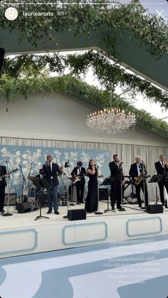 a group of people standing on top of a stage in front of a chandelier