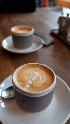 two cups of coffee sitting on top of a white saucer