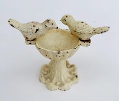 two ceramic birds sitting on top of a white bowl with black spots in it's beaks