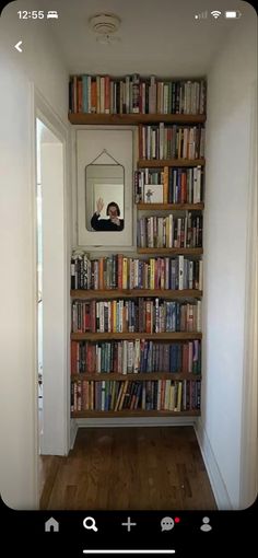 a bookshelf filled with lots of books next to a mirror on the wall