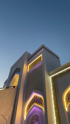 a tall white building with lights on it's sides and arabic writing on the side