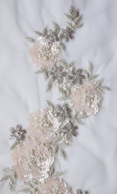 two white flowers with silver leaves on a white cloth covered bed sheet, close - up