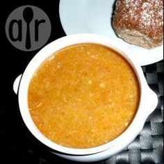 a bowl of soup next to a plate with a piece of bread on the side