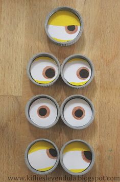 six empty cupcake tins with eyes painted on them sitting on a wooden surface