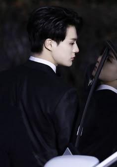 a man in a tuxedo standing next to a car looking out the window