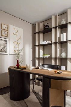 an office desk with bookshelves and vases on the shelves in front of it