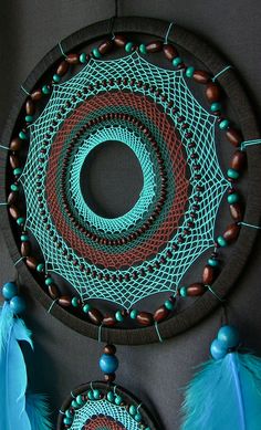 a blue and red dream catcher with feathers hanging from it's sides on a wall