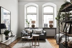 a living room filled with furniture next to two windows and a rug on the floor