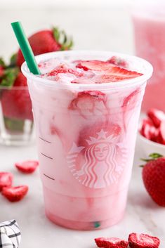 a drink with strawberries and ice in it on a table next to some strawberries