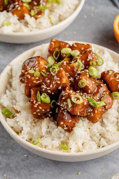 two white bowls filled with rice and meat on top of an orange slice next to another bowl