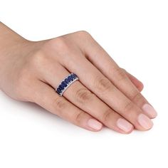 a woman's hand with a blue and white diamond ring on her left hand