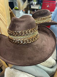 Our love of hats just got became a full-on obsession: meet the Beth Dutton Chain Banded cowboy hat! The most chic, high-end hat we could've ever dreamed up. A hat this good needs to be worn as much as possible and with every single outfit! Hand made by artisans, incredible quality, pure suede, hand placed chain around the crown, too many details to list! The best part? It's super structured with an elastic band on the inside that will fit EVERYONE. Btw never taking this hat off. These hats are a Gold Fedora Western Hat, Western Gold Fedora With Short Brim, Gold Western Fedora Hat, Western Style Gold Fedora With Flat Brim, Western Style Gold Fedora With Short Brim, Western Gold Hat Bands For Party, Western Style Gold Hat Bands For Parties, Gold Flat Brim Hat For Rodeo, Gold Fedora Hat For Rodeo