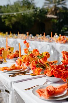 the table is set with orange flowers and place settings for an elegant dinner or reception