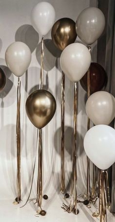 several balloons are lined up in front of each other on the floor with gold and white poles