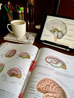 an open book sitting on top of a wooden table next to a cup of coffee