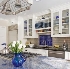 a blue vase filled with white flowers sitting on top of a kitchen counter