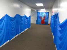 an empty hallway with blue tarps covering the walls and carpeted flooring on both sides