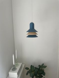 a blue lamp hanging from the ceiling next to a potted plant and candle holder