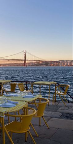 tables and chairs are set up near the water with a view of the golden gate bridge in the background