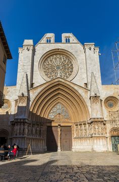 a large cathedral with a clock on it's front door and two people sitting in the doorway