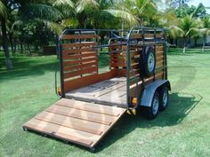 a small trailer is parked on the grass in front of some trees and palm trees