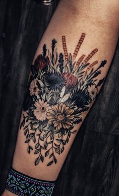 a close up of a person's arm with a tattoo on it and flowers