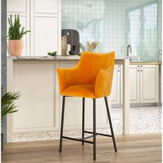 an orange chair sitting on top of a wooden floor in front of a kitchen counter