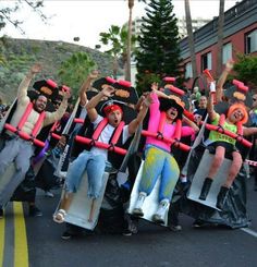 a group of people riding on top of skateboards down a street with arms in the air