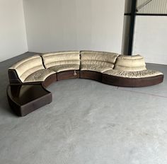 a large sectional couch sitting on top of a cement floor in an empty room with no one around it