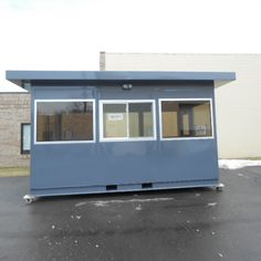 a small blue building sitting in the middle of a parking lot