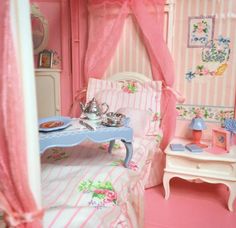 a dollhouse bedroom with pink walls and furniture, including a tea set on the bed