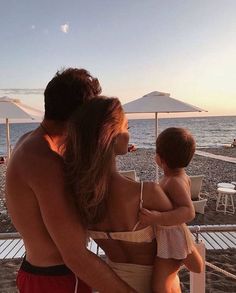 a man holding a baby on the beach