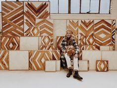 a woman sitting in front of a wall made out of wood blocks with a dog on her lap