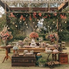 an outdoor dessert table is set up with pink flowers and greenery on the tables