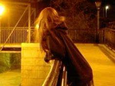 a woman standing next to a railing at night