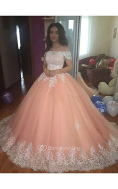 a woman standing in front of a mirror wearing a pink ball gown with white lace