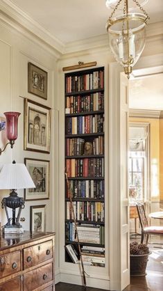 a living room filled with lots of furniture and bookshelf next to a lamp