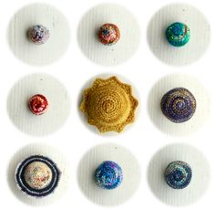 nine crocheted balls arranged in rows on a white surface, each with different colors