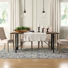 a dining room table with two chairs and a bowl on it, in front of windows