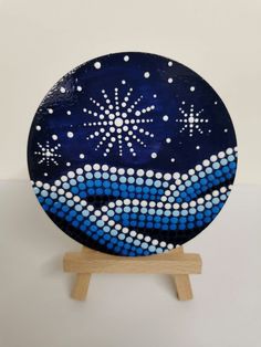 a blue plate with white dots and snowflakes on it sitting on a wooden stand