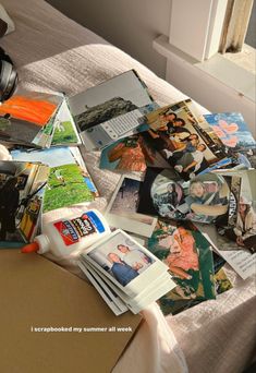 a bed covered in lots of different pictures and papers next to a window with a camera on top of it