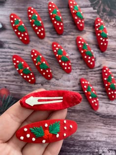 someone is holding a red christmas manicure with holly leaves on it and white dots