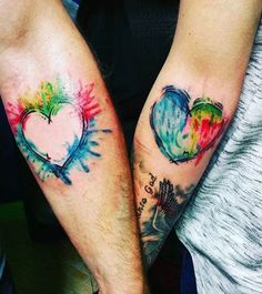 two people with tattoos on their arms holding each other's hands and one has a heart