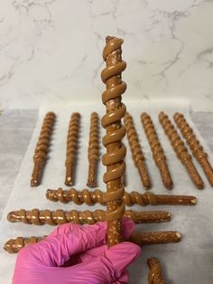 a person in pink gloves is making a sculpture out of doughnuts and sticks