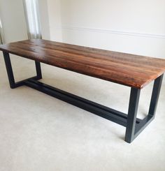 a wooden table sitting on top of a white carpeted floor next to a window