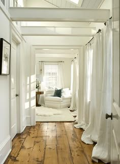 a white room with wood floors and curtains