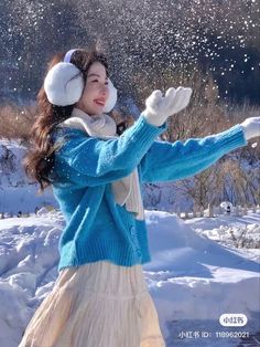 a woman standing in the snow with her arms outstretched and headphones up to her ear