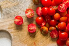 tomatoes on a cutting board next to a spoon