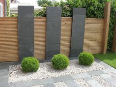 some bushes and rocks in front of a wooden fence