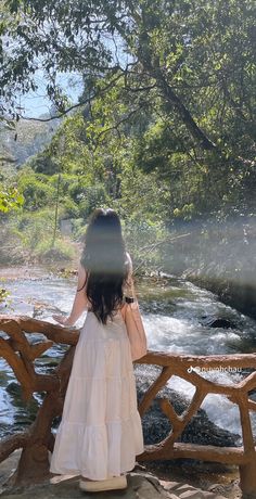 a woman standing on a wooden bridge over a river